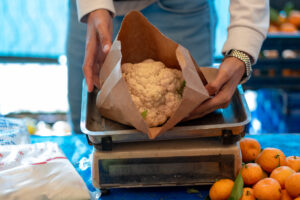 Person weighing cauliflower in a reusable paper bag