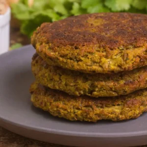 lentil mushroom burger patties stacked on a plate with cilantro and dried lentils in the background